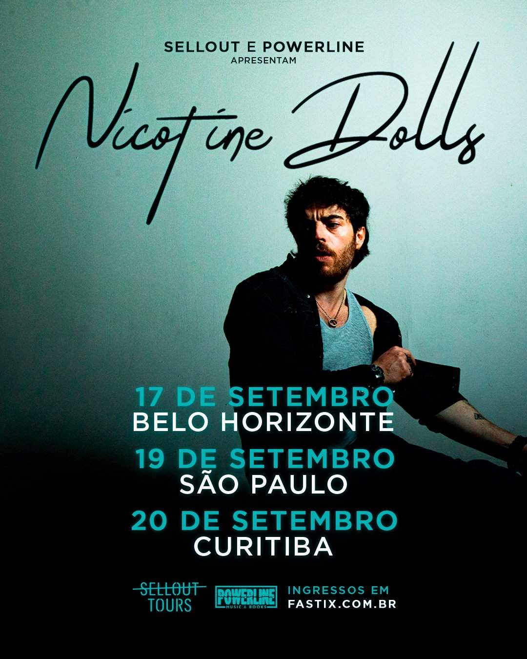 Plano médio de Sam Cieri, vocalista do Nicotine Dolls, sentado e posando contra uma parede azul
